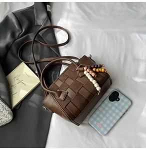 Detail of dark brown woven texture handbag with wooden bead tassel and crossbody strap