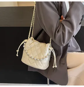 Detail of quilted bucket bag with pearl handle, chain strap, and triangle metal logo