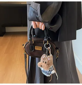 Detail of suede baguette bag featuring teddy bear charm and gold logo plate