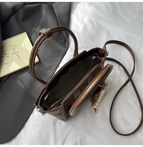 Top view of brown leather tote bag interior with zip pocket and wooden bead charm accessory