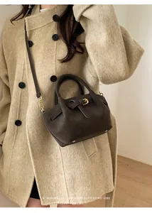 Detailed view of deep coffee leather handbag styled with an elegant beige winter coat