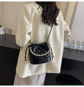 Close-up of quilted black bucket bag with pearl chain and metallic fashion logo details