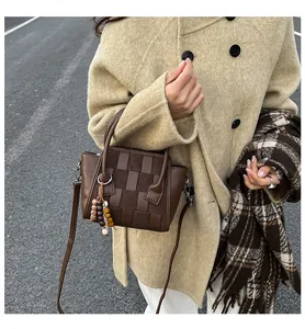 Detailed woven leather handbag in brown with vintage bead charm and crossbody strap