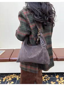 Detail of vintage brown hobo bag featuring contrast stitching and stylish letter charms