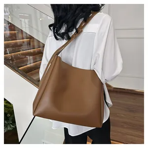 Detail view of large brown leather tote bag with adjustable shoulder strap and matte finish