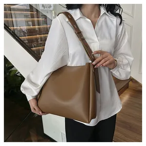Detailed shot of brown matte leather tote bag with adjustable wide shoulder strap on model