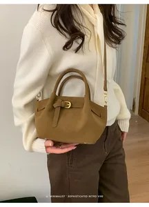 Detail shot of a retro caramel brown tote bag with decorative buckle and golden hardware