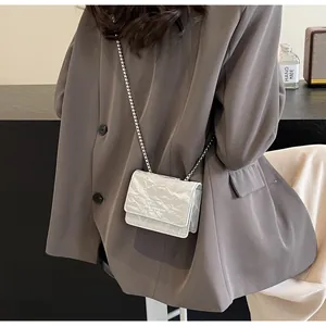 Dettaglio della mini borsa a tracolla argento metallizzato con trama a pieghe e catena