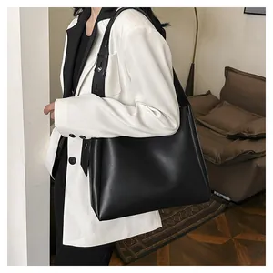 Minimalist black matte leather tote bag with adjustable shoulder strap on a model