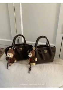 Detail of dark brown retro handbags with teddy bear charms on a textured beige sofa