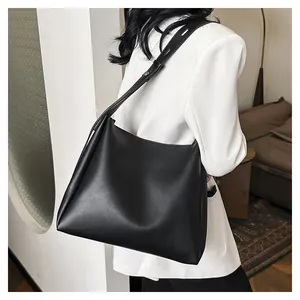 Detail of minimalist black tote bag featuring a wide adjustable strap and matte finish
