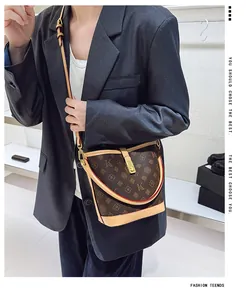 Detail of printed bucket bag with metal clasp and contrast leather strap on a model
