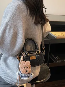 Elegant black oval baguette bag with gold hardware and a cute teddy bear charm