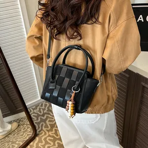 Minimalist black woven crossbody bag with wooden bead charm and stylish leather textures
