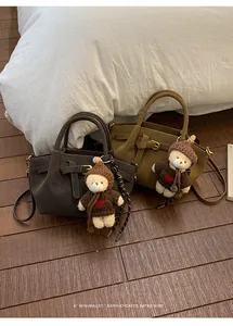 Detail view of vintage matte leather handbags with decorative bear charms on soft bedding