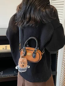 Brown leather baguette bag with black trim and cute plush puppy charm accessory