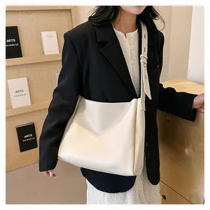 Chic cream leather tote bag shown with an adjustable strap in a minimalist office setting