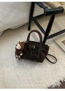 Detailed close-up of dark brown suede bucket bag with leather straps and bear charm