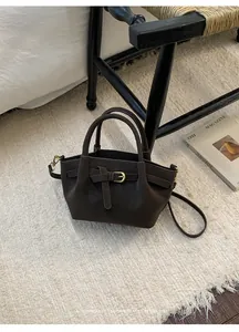 Close-up of dark brown suede bucket bag with gold hardware buckle and leather strap details