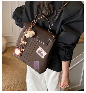 Détail du sac cabas marron avec écussons de dessin animé et porte-clés ours en peluche