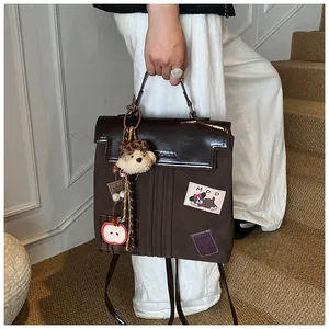 Détail du sac à dos marron avec écussons de dessins animés et pendentif ours sur l'escalier