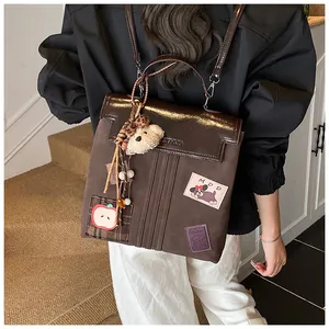 Détail d'un sac à dos patchwork marron foncé avec texture en daim, broderies et breloque ours