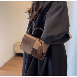 Detalle de bolso bandolera de cuero marrón con texturas mixtas llevado por una modelo