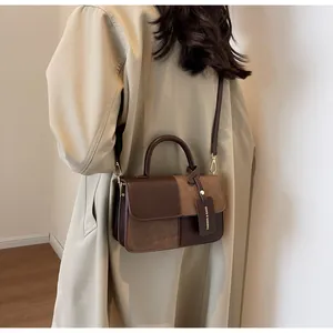 Detalle de bolso bandolera bicolor combinado con una gabardina beige de estilo chic