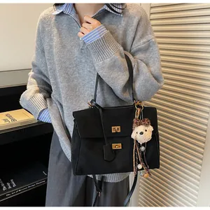 Detalle de bolso tote negro vintage con cierre giratorio dorado y colgante de oso de peluche