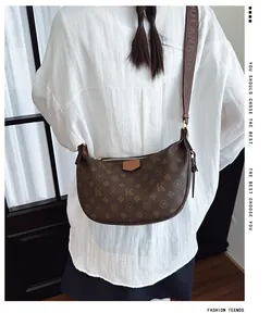 Detail of dark brown crescent bag featuring vintage monogram pattern and wide shoulder strap