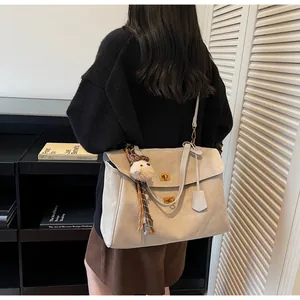 Detalle de bolso tote de ante beige con cierres de giro, colgante de oveja y pañuelo de leopardo