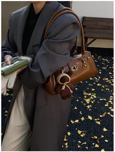 Detalle de un bolso baguette vintage marrón con colgante de oso de peluche y cierre de latón