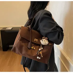 Detalle de bolso tote vintage de ante marrón con cierres dorados y colgante de osito