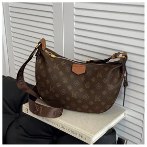 Detailed view of the brown monogrammed leather texture and wide fabric shoulder strap