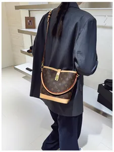 Detail view of printed bucket bag worn by model with gold lock and adjustable strap