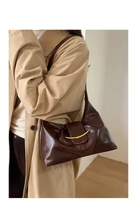 Détail du sac baguette en cuir glacé marron foncé avec boucle métallique en croissant doré