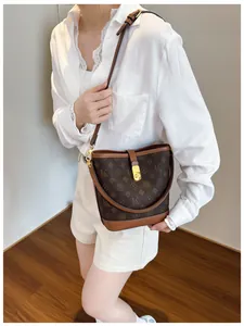 Brown monogram bucket bag with gold hardware worn as a stylish crossbody purse