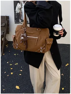 Detail of a brown large capacity tote bag with metal buckles and vintage biker style
