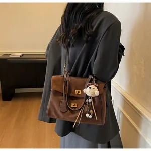 Detalle del bolso tote vintage de ante marrón con cierres de giro y adorno de oso
