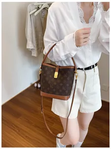 Detail showing printed bucket bag with brown monogram pattern and metal clasp closure