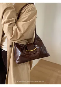 Gros plan sur le sac baguette rétro en cuir ciré marron foncé avec boucle dorée chic