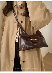 Détail du sac en cuir verni marron foncé avec boucle métallique dorée et bandoulière