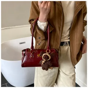 Detalle de bolso de hombro rojo brillante con cierre dorado y colgante de osito