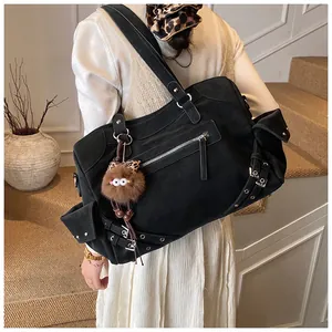 Detail of black motorcycle style tote bag with rivets and fuzzy monster charm