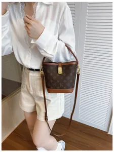 Fashionable brown printed bucket bag with adjustable strap worn by model in a stylish setting