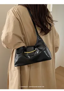 Vue latérale d'un sac baguette vintage noir brillant porté sur un trench-coat