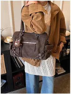 Detail of dark brown tote bag with metal buckles, multi-pockets and plush charm