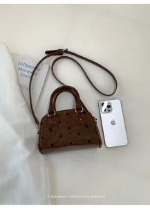 Detailed view of brown tweed baguette bag with polka dot bow embroidery and leather trim