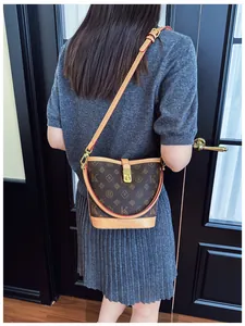 Classic monogram bucket bag shown on shoulder with elegant brown leather trim