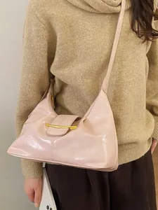 Sac baguette rose minimaliste rétro avec boucle dorée porté par un mannequin féminin